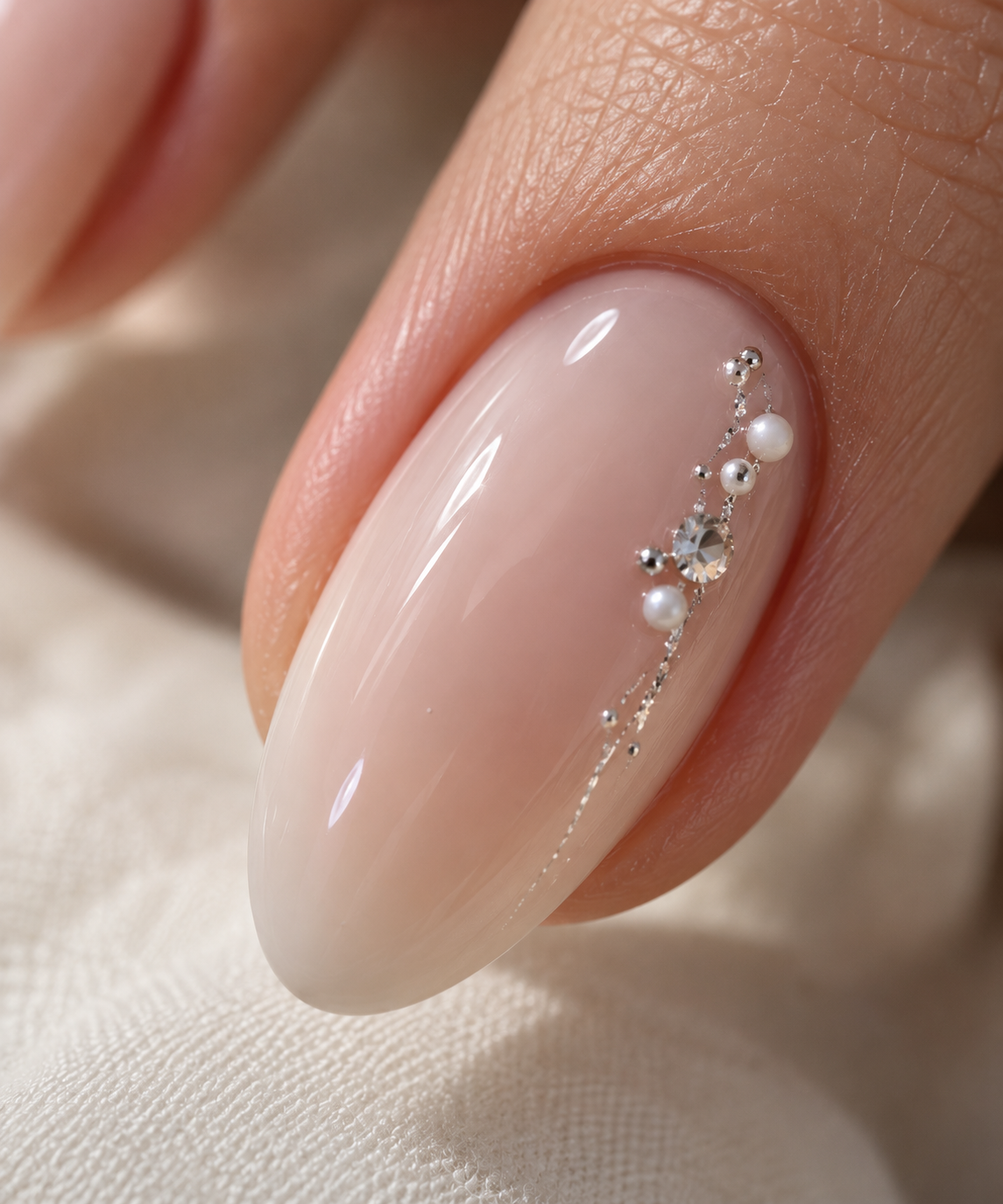 Ongle nude orné de perles, cristal et fine chaîne argentée, réalisation d’Anabelle